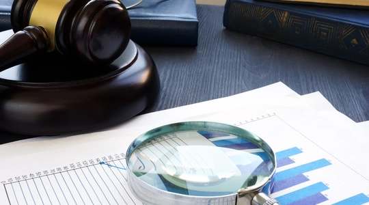 Gavel and Magnifying glass with business documents.