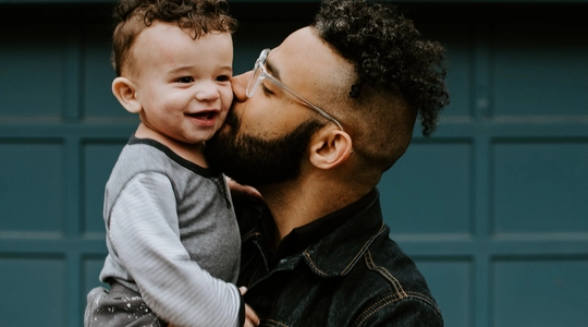 father kissing baby son on cheek