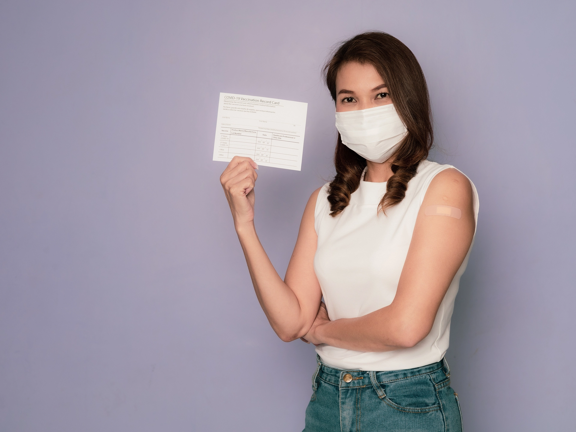 Woman wearing hygiene mask and carrying vaccination card