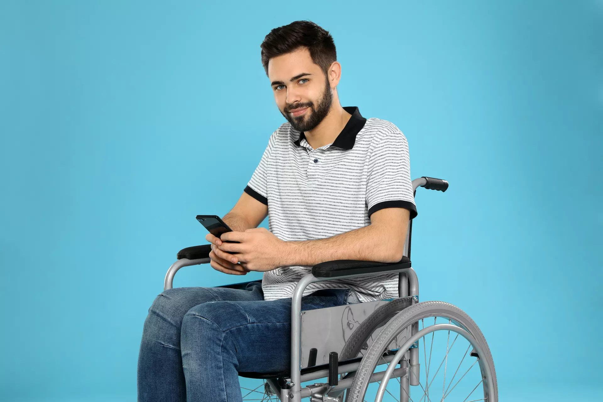Young man with smartphone in wheelchair