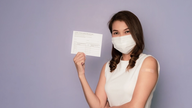 Woman wearing hygiene mask and carrying vaccination card