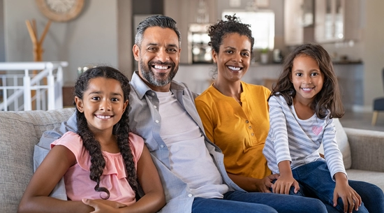 Portrait of cheerful ethnic family at home sitting on sofa