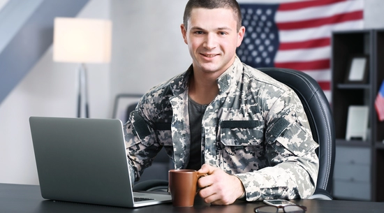 A person in army fatigues at table with laptop
