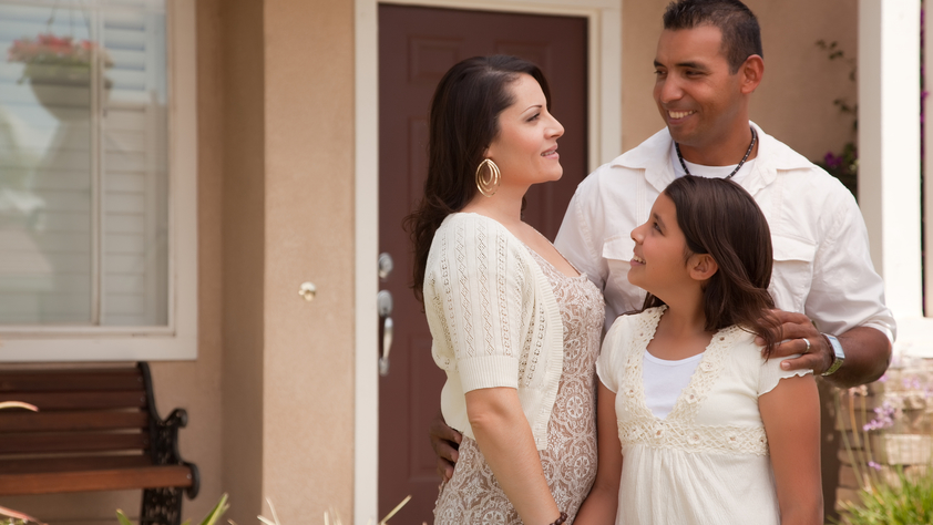 Mother, father, and daughter in front of house